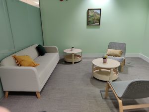 Wellbeing Room level 2 b85 with sofa with cushions, two armchairs, and two tables